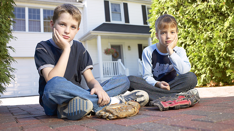 Bored children sitting on driveway