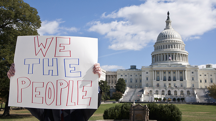 Un manifestante sosteniendo una pancarta frente al edificio del Capitolio de los Estados Unidos.