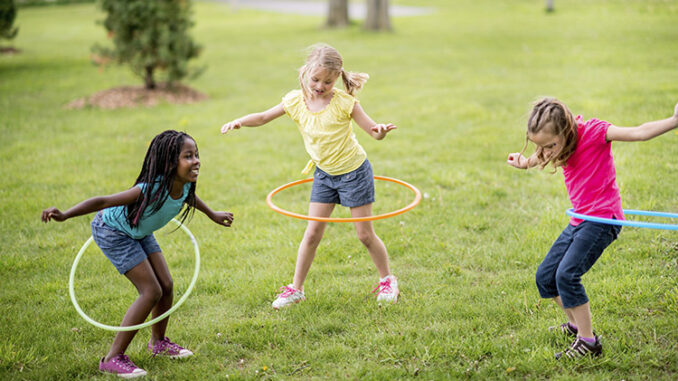 Girls twirling toy hoops around their waists