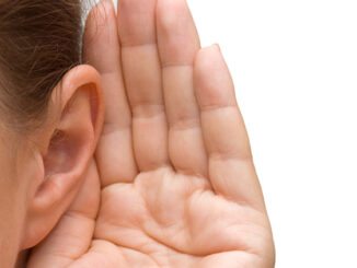 A person holds their hand behind their ear