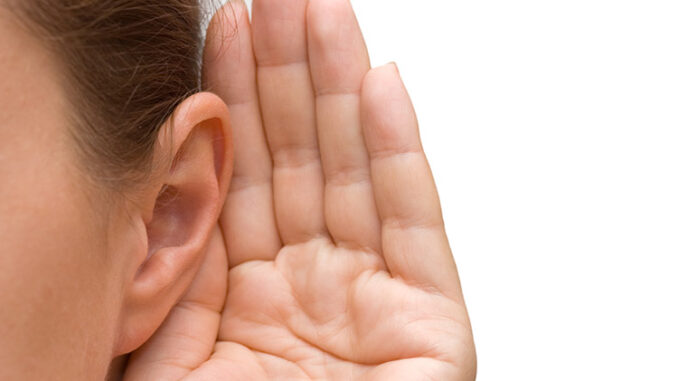 A person holds their hand behind their ear